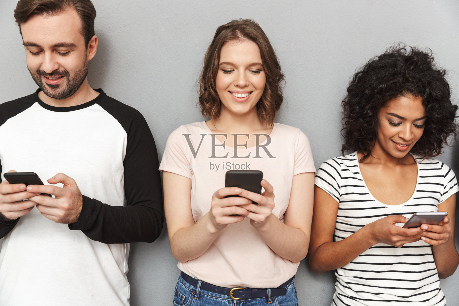 一群情绪开朗的朋友用手机看向一边。照片摄影图片