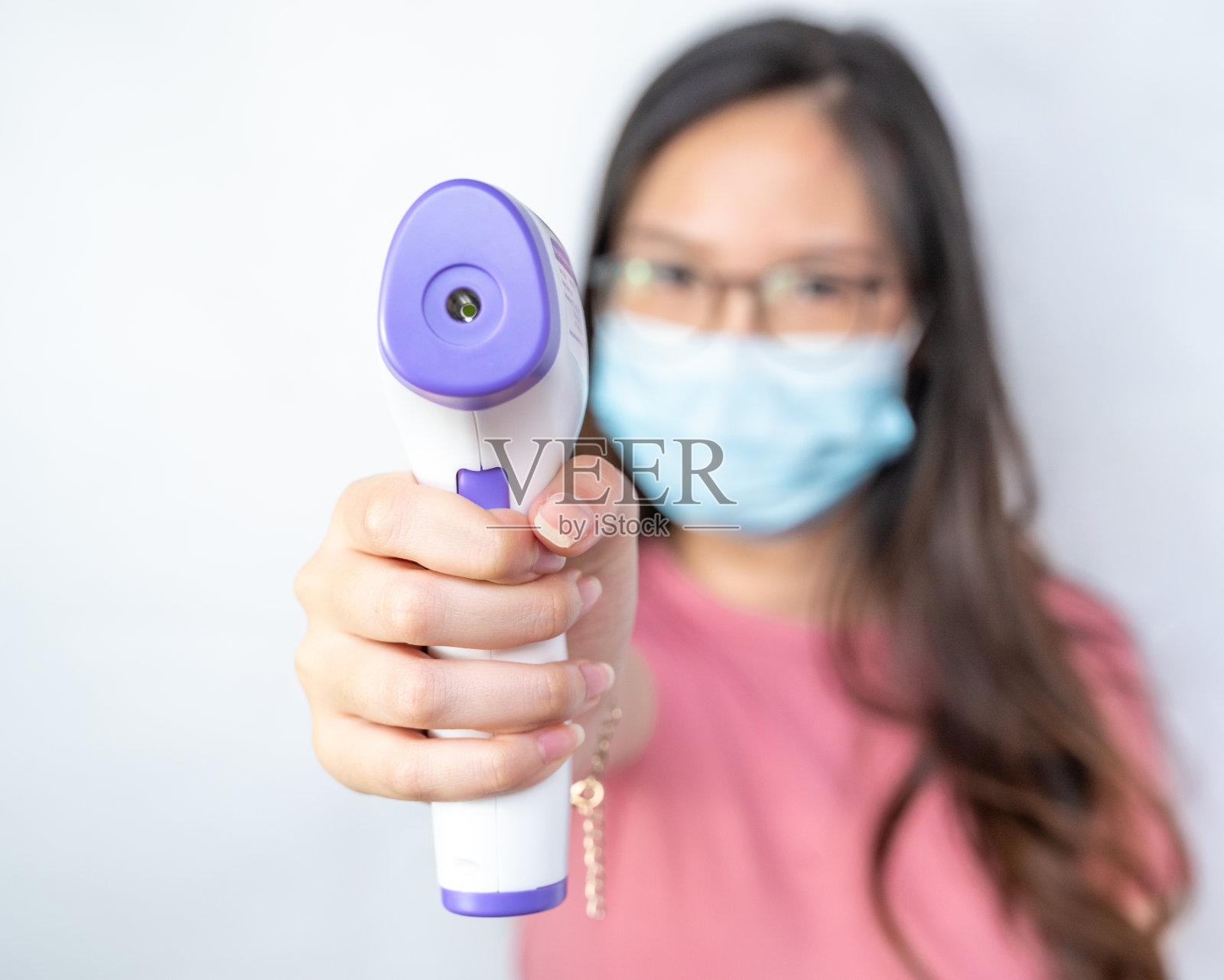 女人拿着红外测温枪，用来测量别人的温度。照片摄影图片