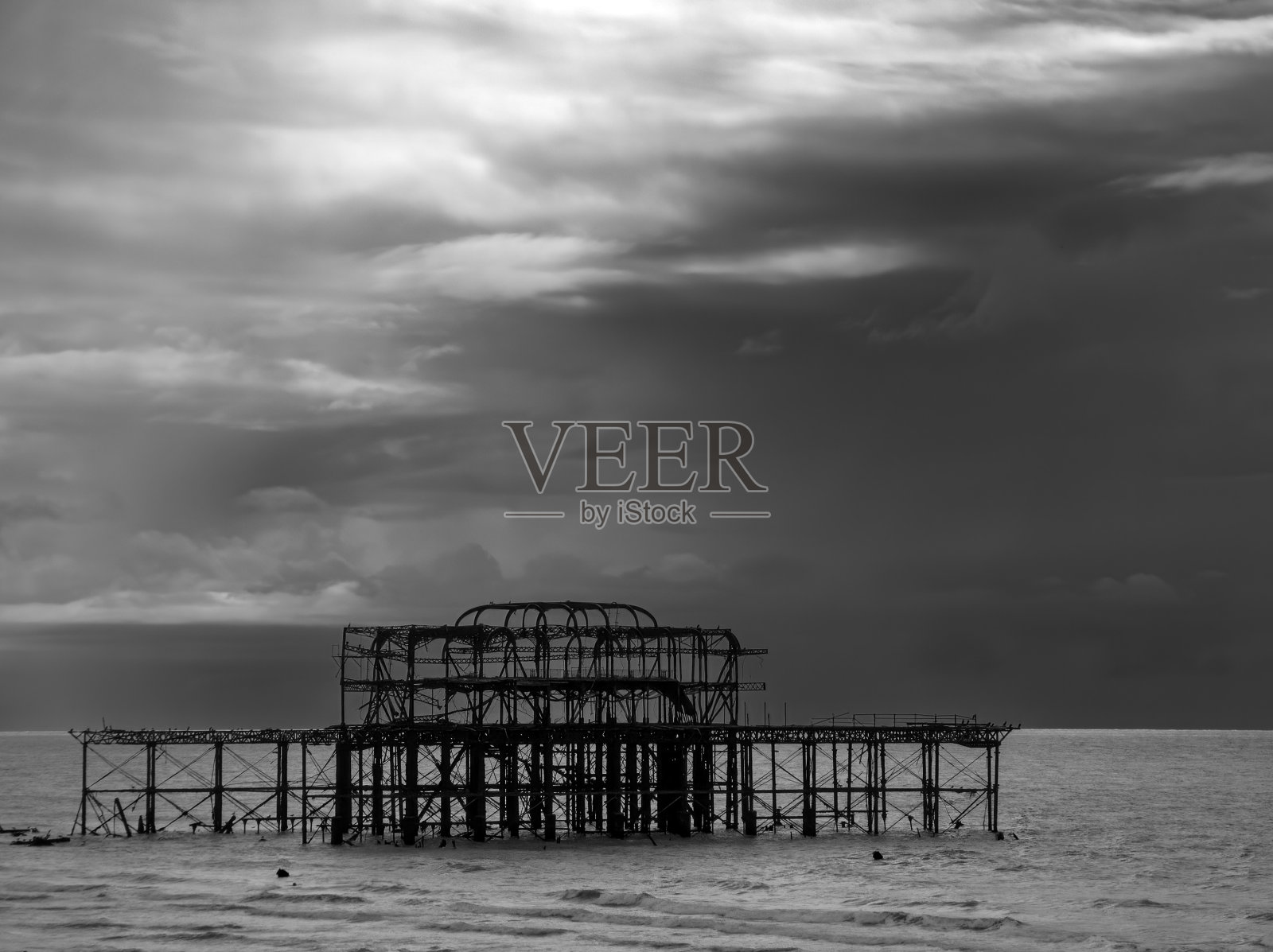 布赖顿西码头的剪影，在黑暗，阴沉的天空下照片摄影图片