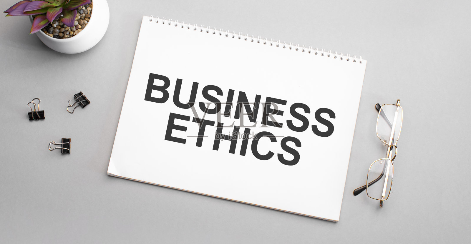 商业道德写在一本白纸上，旁边有一支铅笔、一副黑框眼镜和一株绿色植物。照片摄影图片