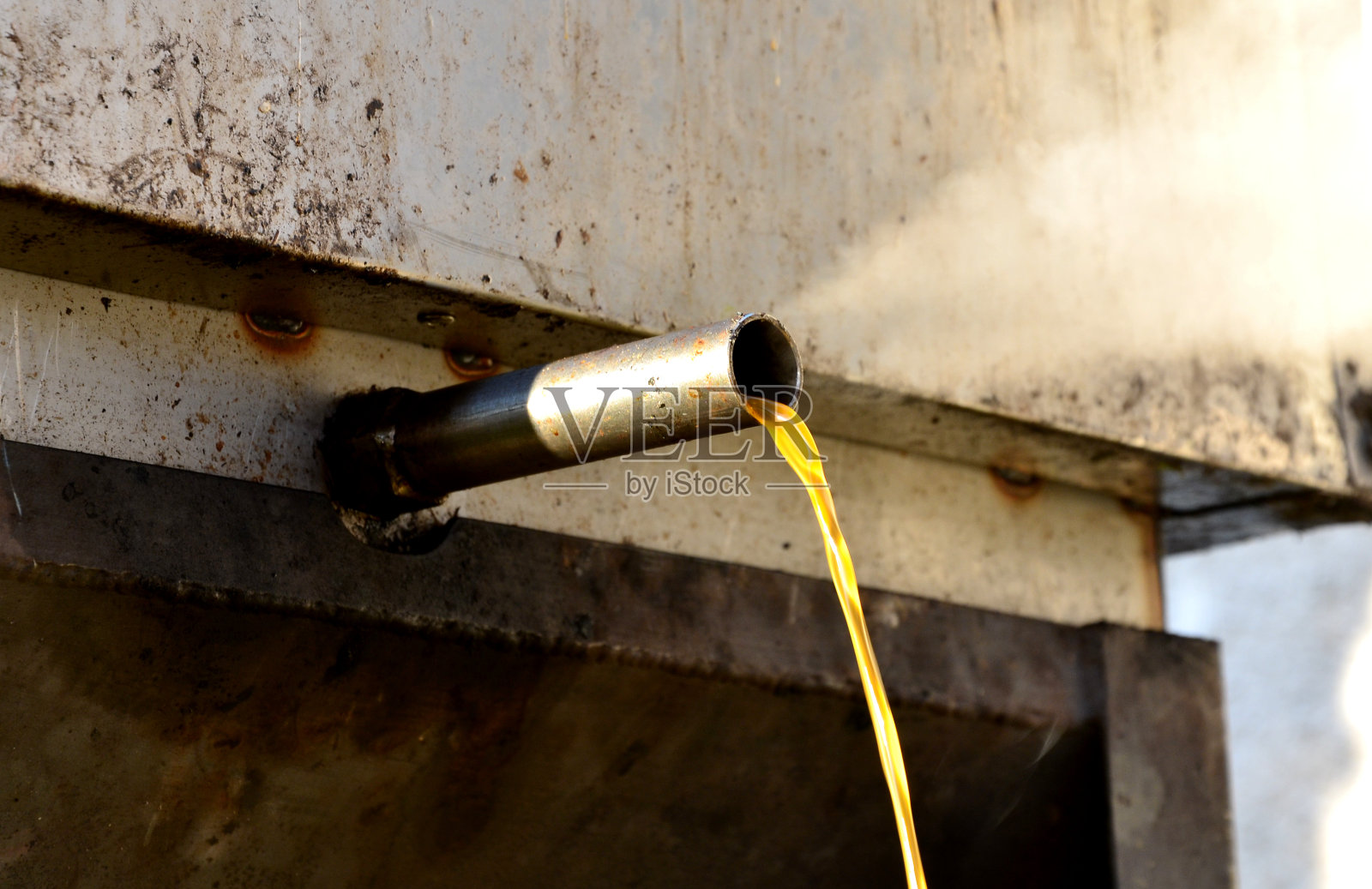 养蜂人在不锈钢蒸汽锅炉中熔化老旧的黑蜡梳。蜡在热蒸汽中融化，通过一根管子流出到一个容器中，在那里凝固照片摄影图片