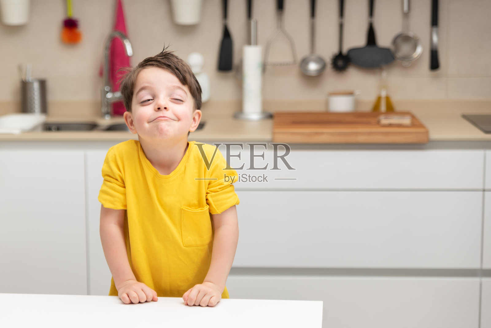 穿黄衬衫的小男孩在厨房里想着要做什么照片摄影图片