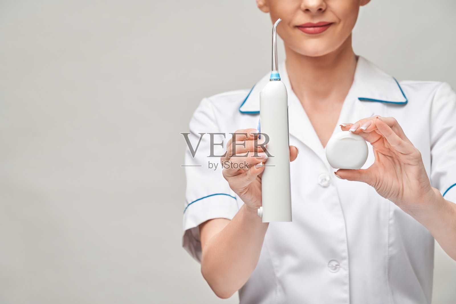 年轻女医生拿着牙线牙齿清洁线盒，用于清洁牙齿和冲洗器——牙齿保健和卫生照片摄影图片