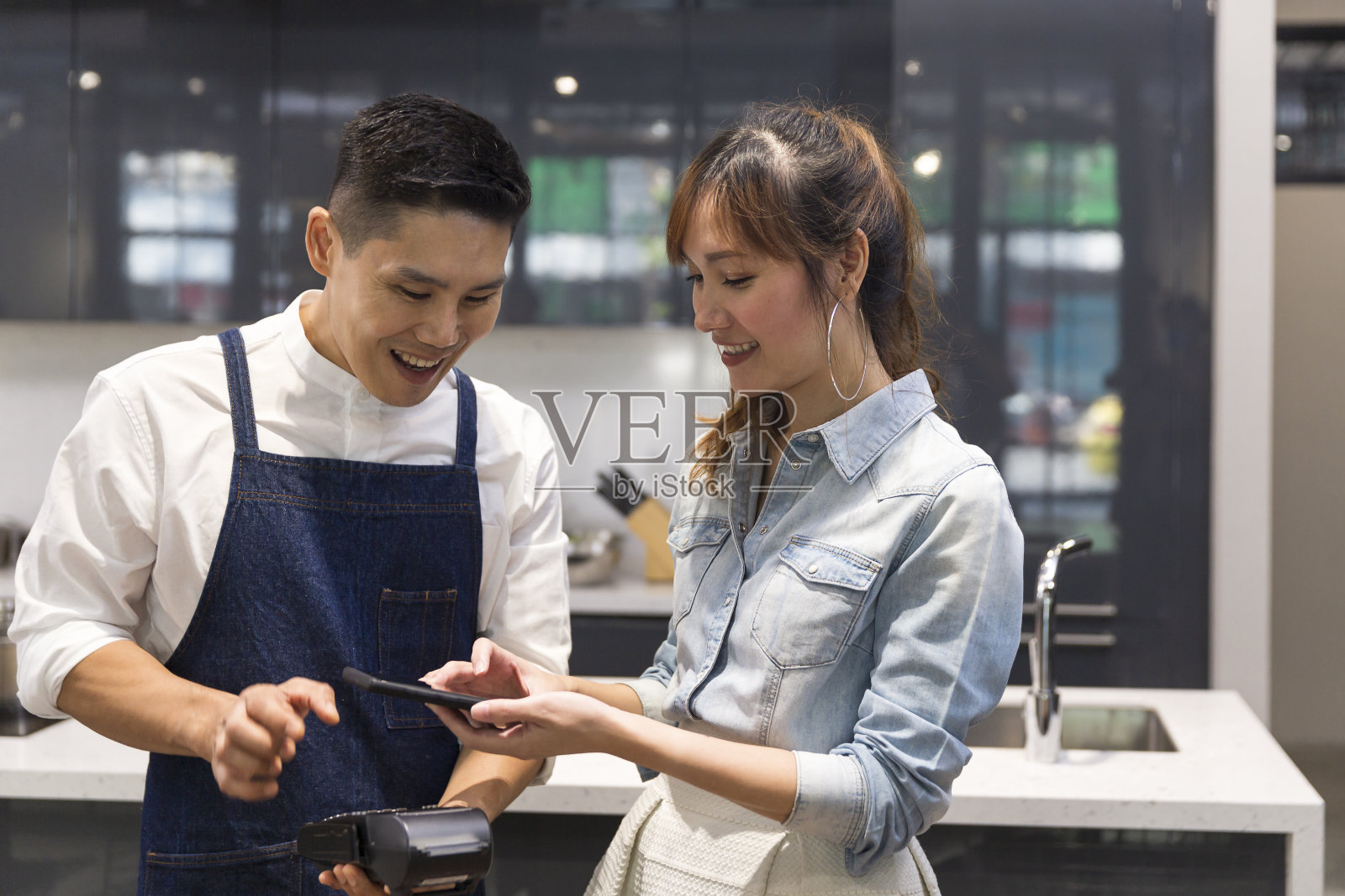 非接触式支付。女顾客用手机扫描付款。一名女子在咖啡店用手机付款。移动支付在线购物。照片摄影图片