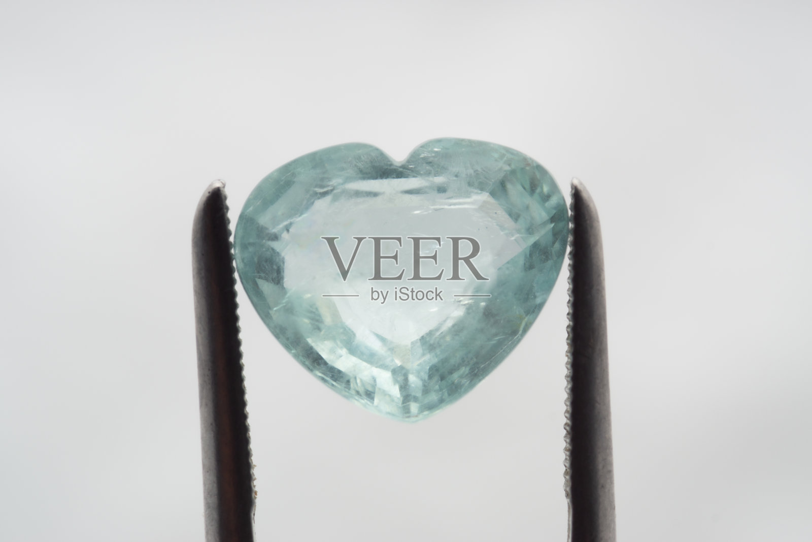 在白色背景的镊子上的天然石海蓝宝石照片摄影图片