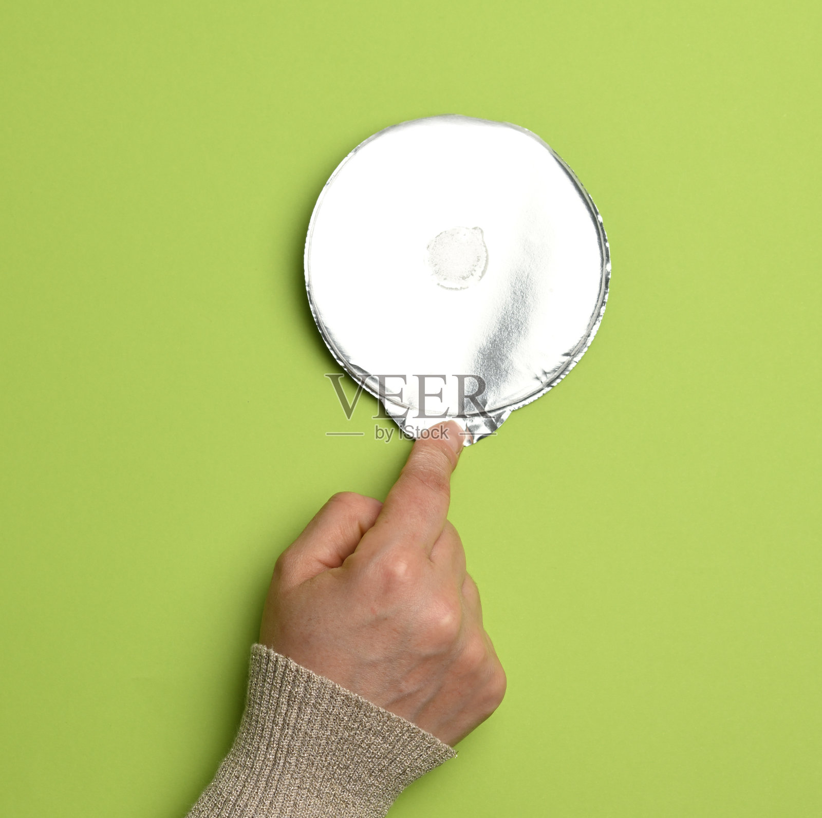 绿色背景上的塑料酸奶罐的圆形铝薄盖照片摄影图片