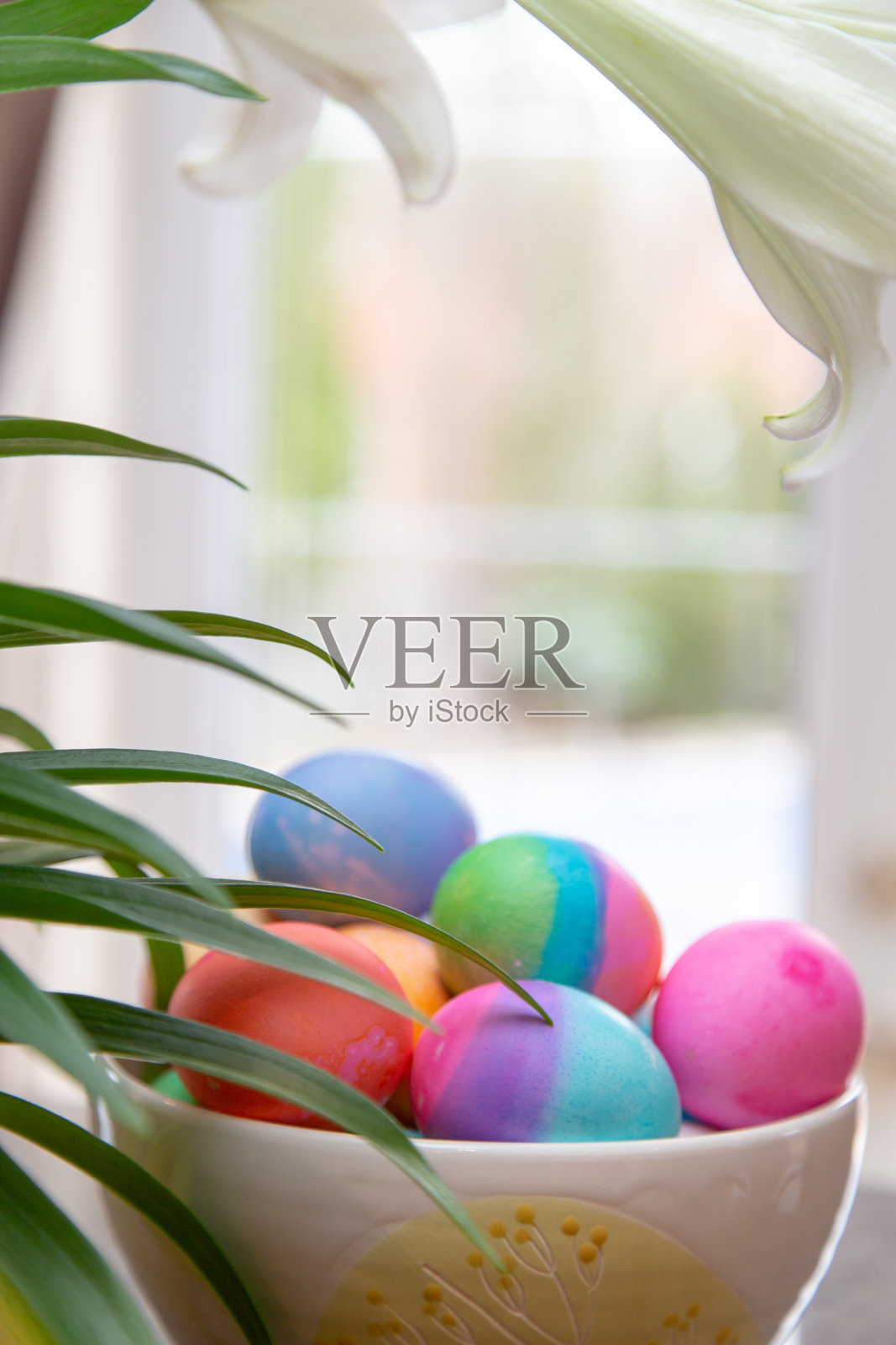 厨房窗户上摆着一碗色彩鲜艳的复活节彩蛋照片摄影图片