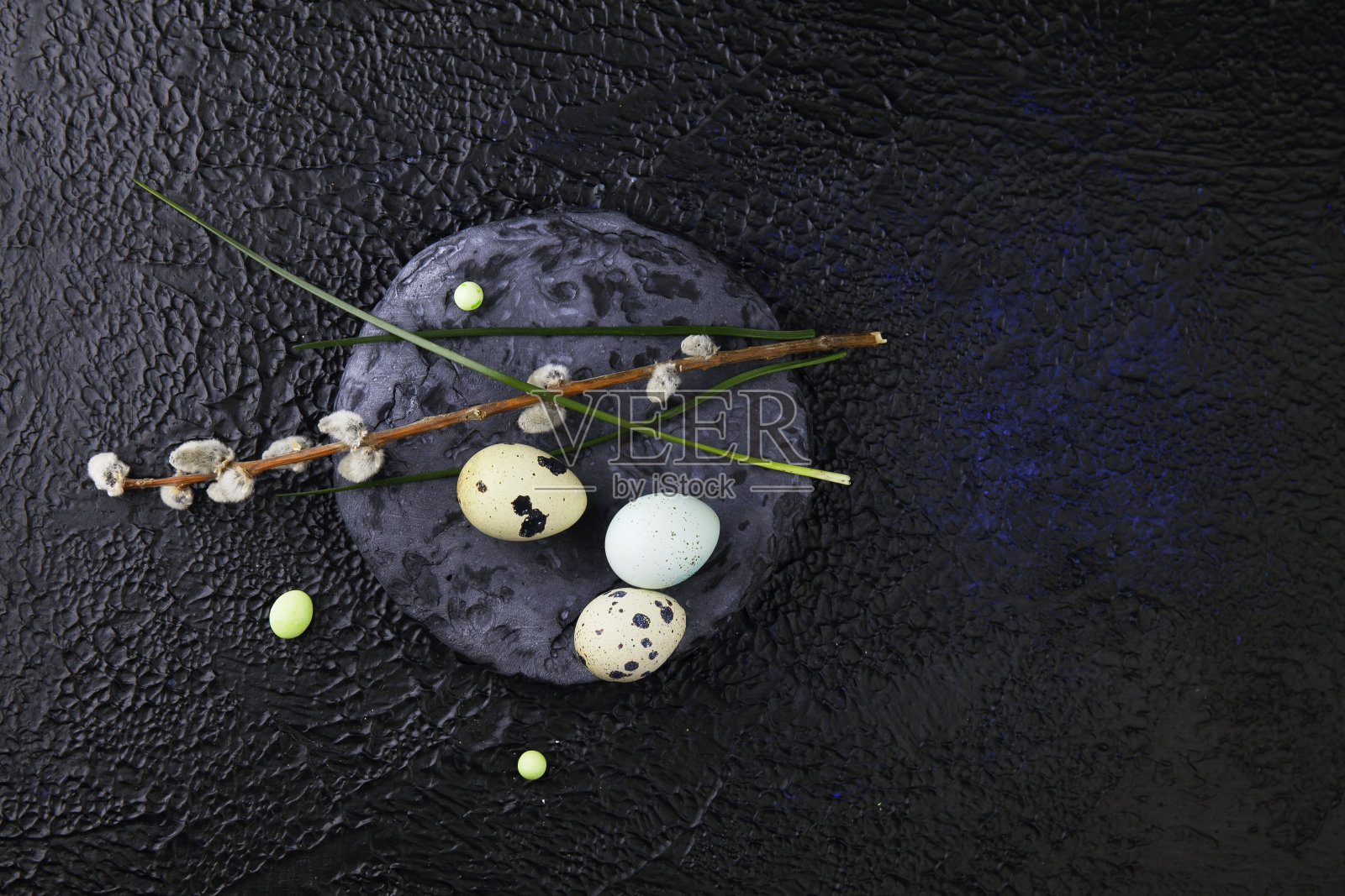 复活节彩蛋和猫咪柳枝站在一个圆形石板石上，在一个深色纹理的背景顶视图照片摄影图片