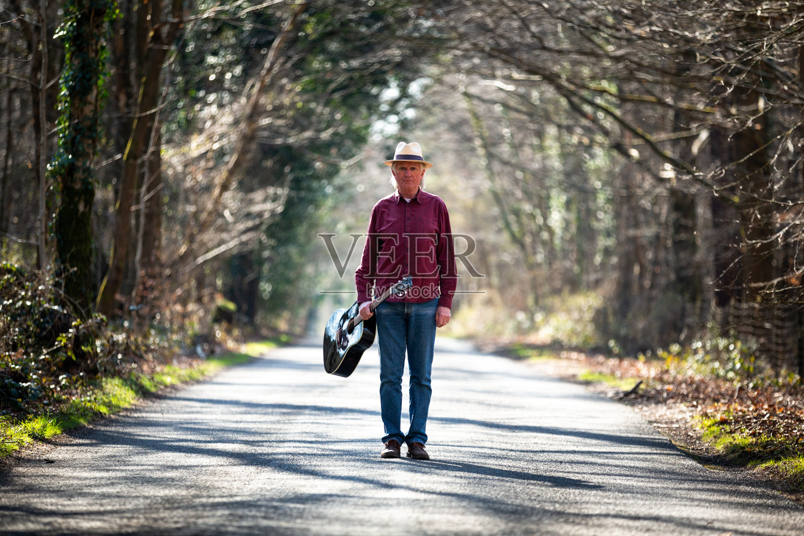 一个带着原声吉他在乡村路上自由漫步的人照片摄影图片
