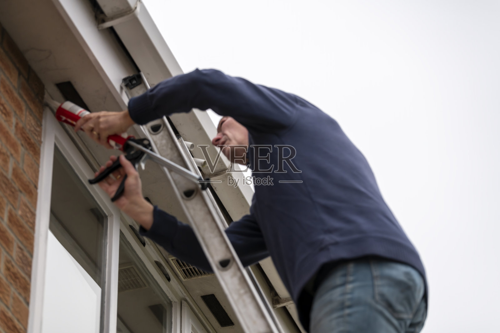 高级人员在漏水的窗户周围涂密封胶照片摄影图片