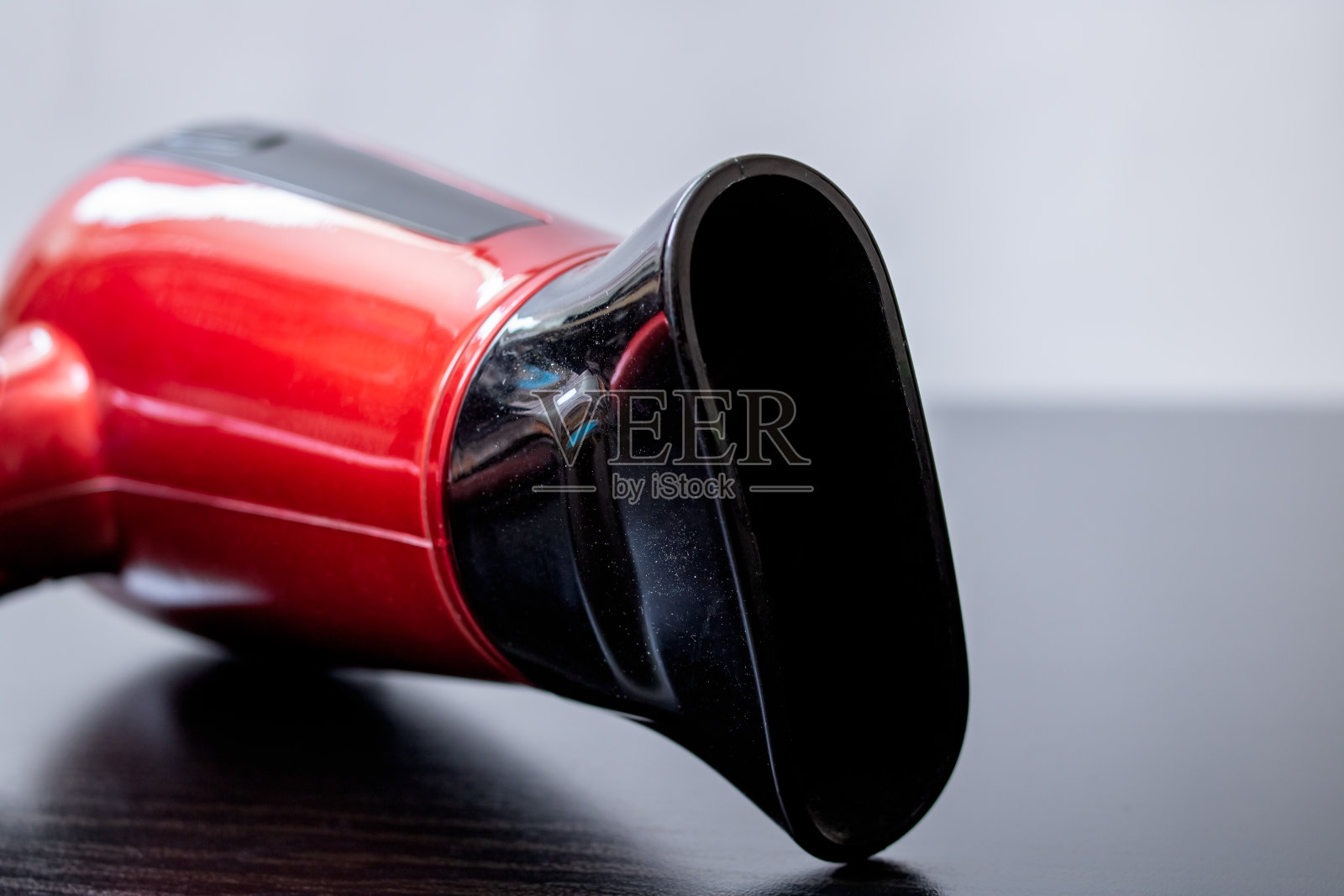 黑色木桌上放着红色吹风机照片摄影图片