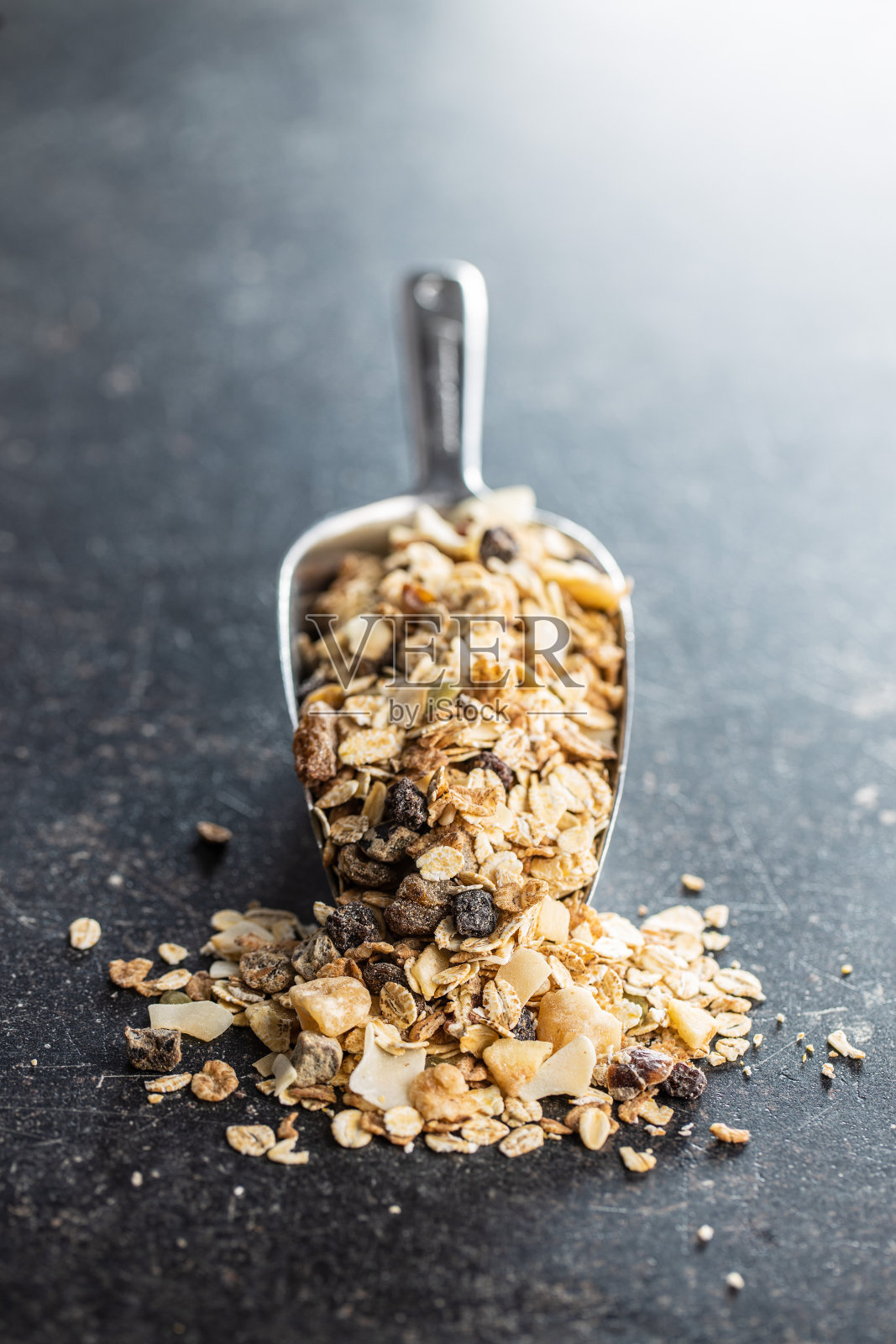 早餐麦片勺。含有燕麦片、坚果和葡萄干的健康麦片照片摄影图片