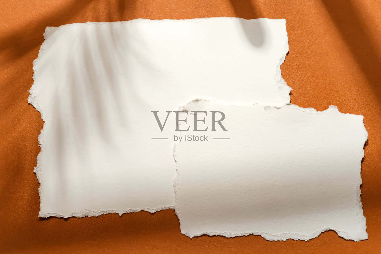 撕破的白纸在白色的背景和阴影在棕色的背景照片摄影图片