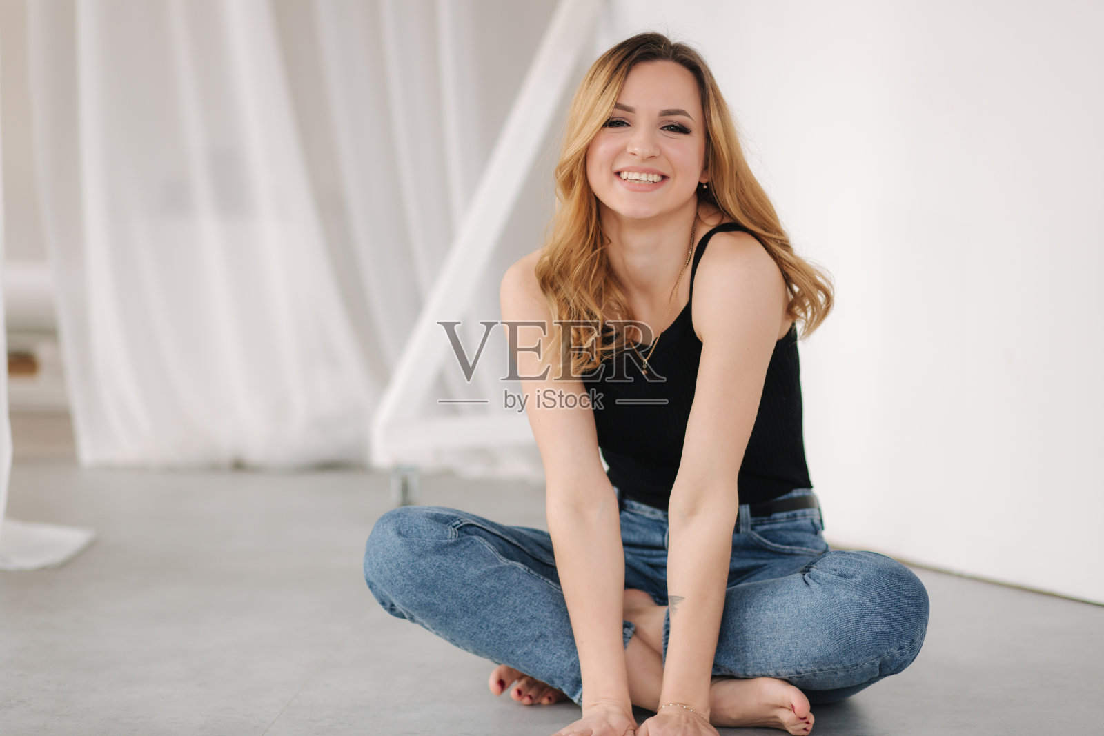 漂亮的年轻女人光着脚在工作室里。幸福的女照片摄影图片