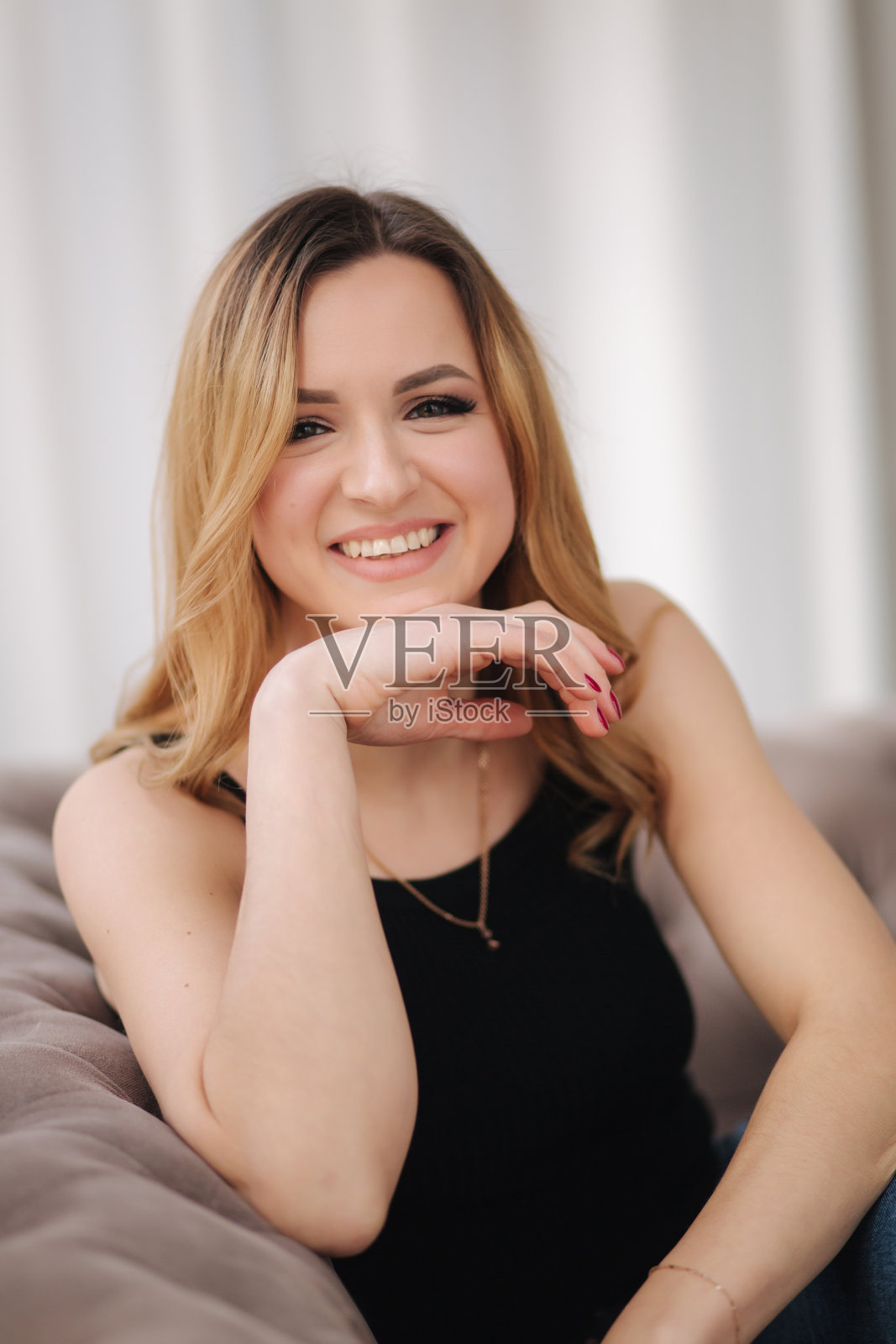 年轻迷人的女人坐在家里的沙发上的肖像照片摄影图片