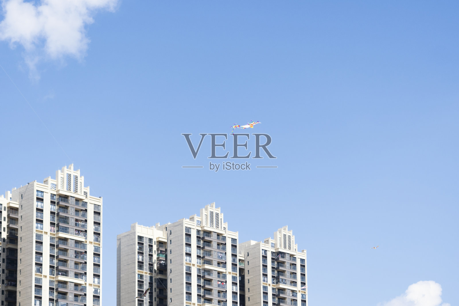 蓝天白云下，居民楼间风筝飞舞照片摄影图片