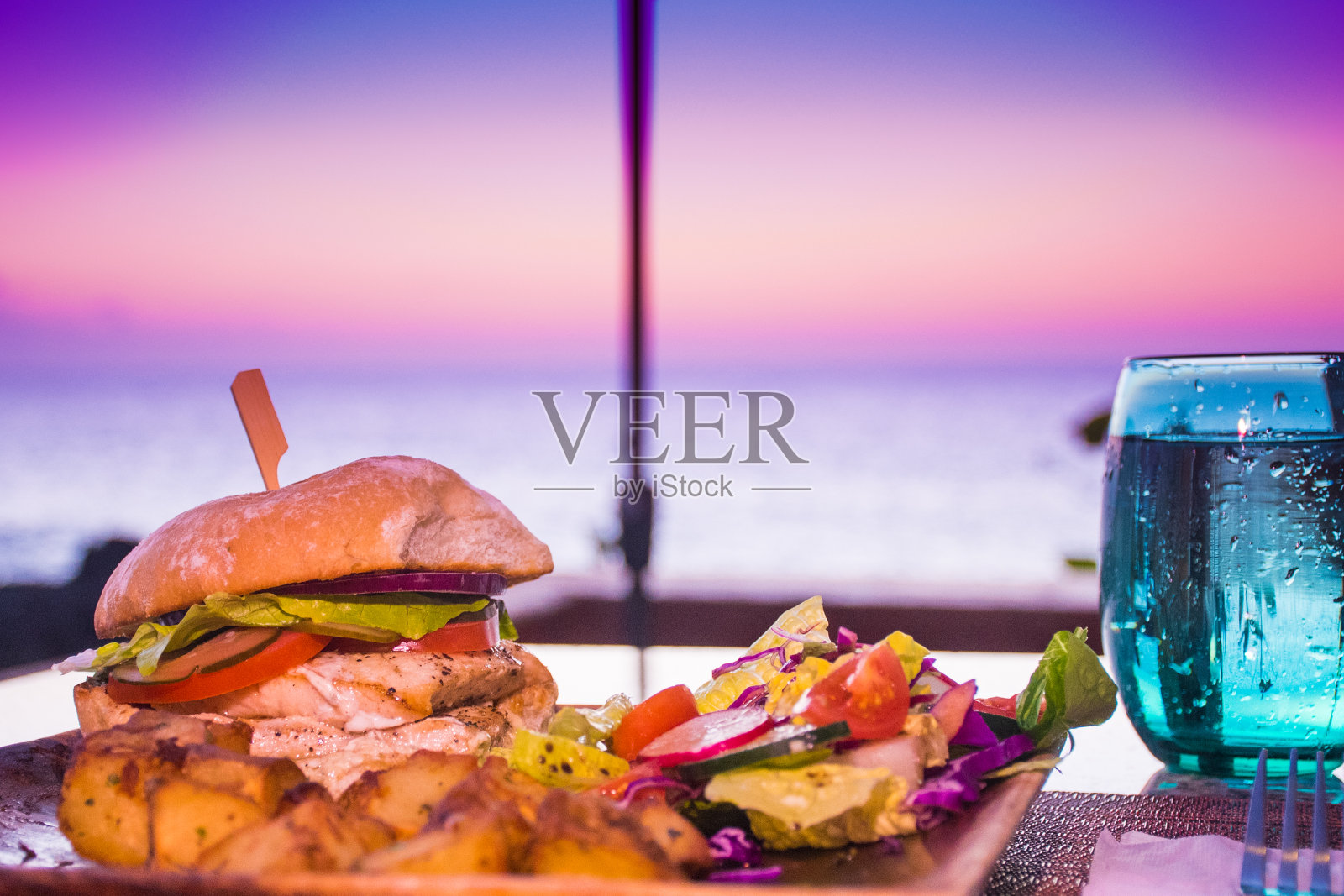 日落时分，户外桌上的鱼三明治照片摄影图片