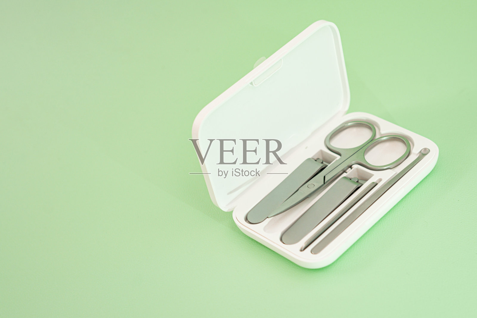 白色的盒子与剪刀和指甲钳放置在绿色的背景照片摄影图片