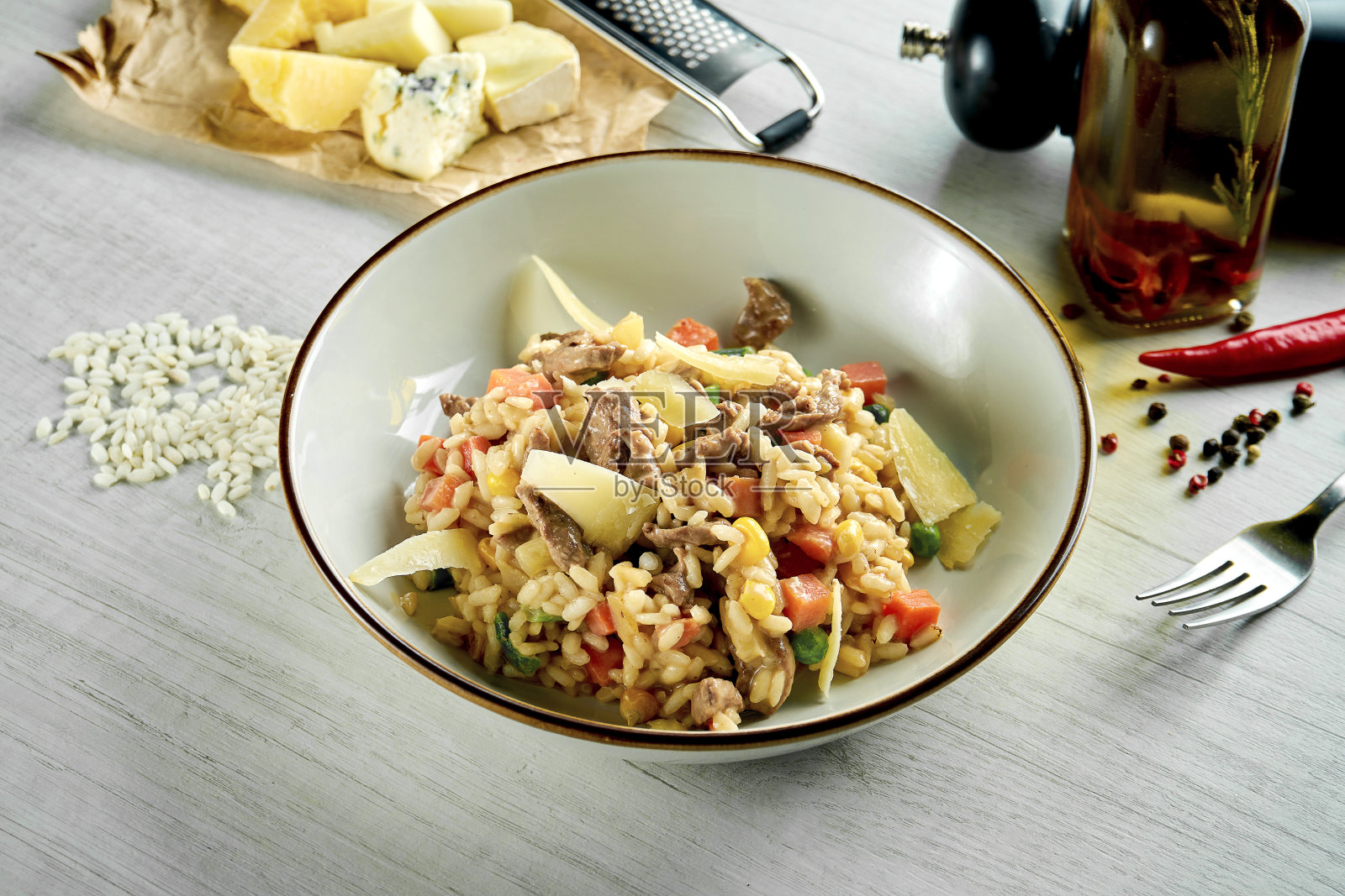 经典的意大利调味饭，配上帕尔马干酪，奶油酱，牛肉和蔬菜，盛在一个白色的碗里，背景是木制的。餐厅的食品照片摄影图片