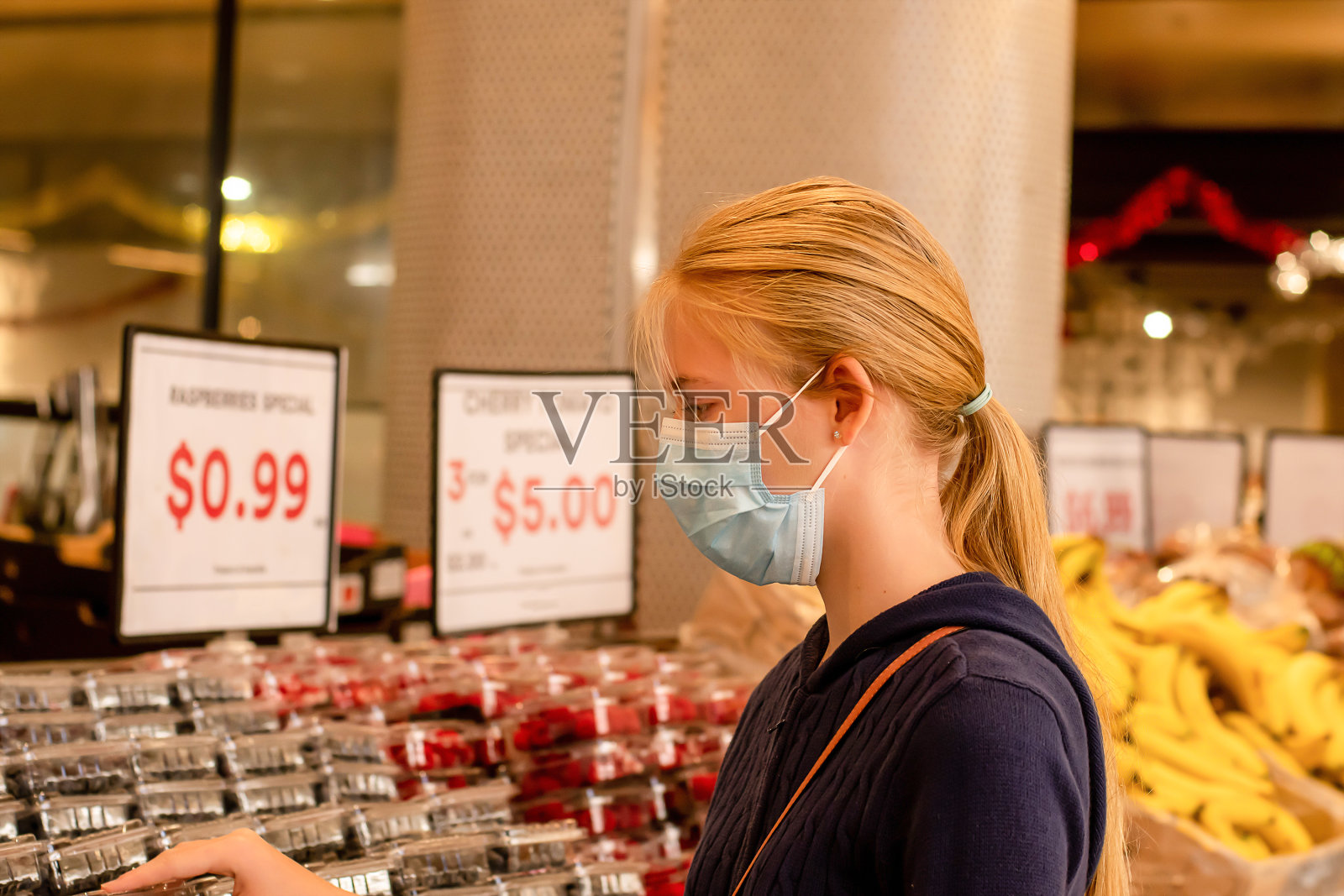 在大悉尼新南威尔士州，购物中心必须戴口罩。一个女孩戴着一次性口罩在杂货店里照片摄影图片