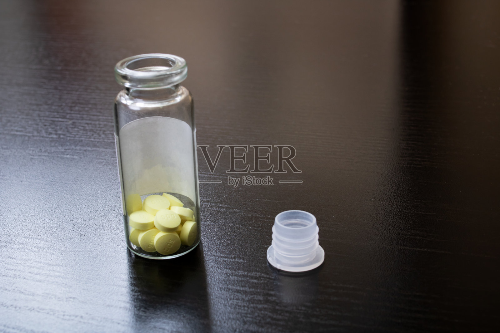 黄色药片装在桌上开着的玻璃罐里照片摄影图片