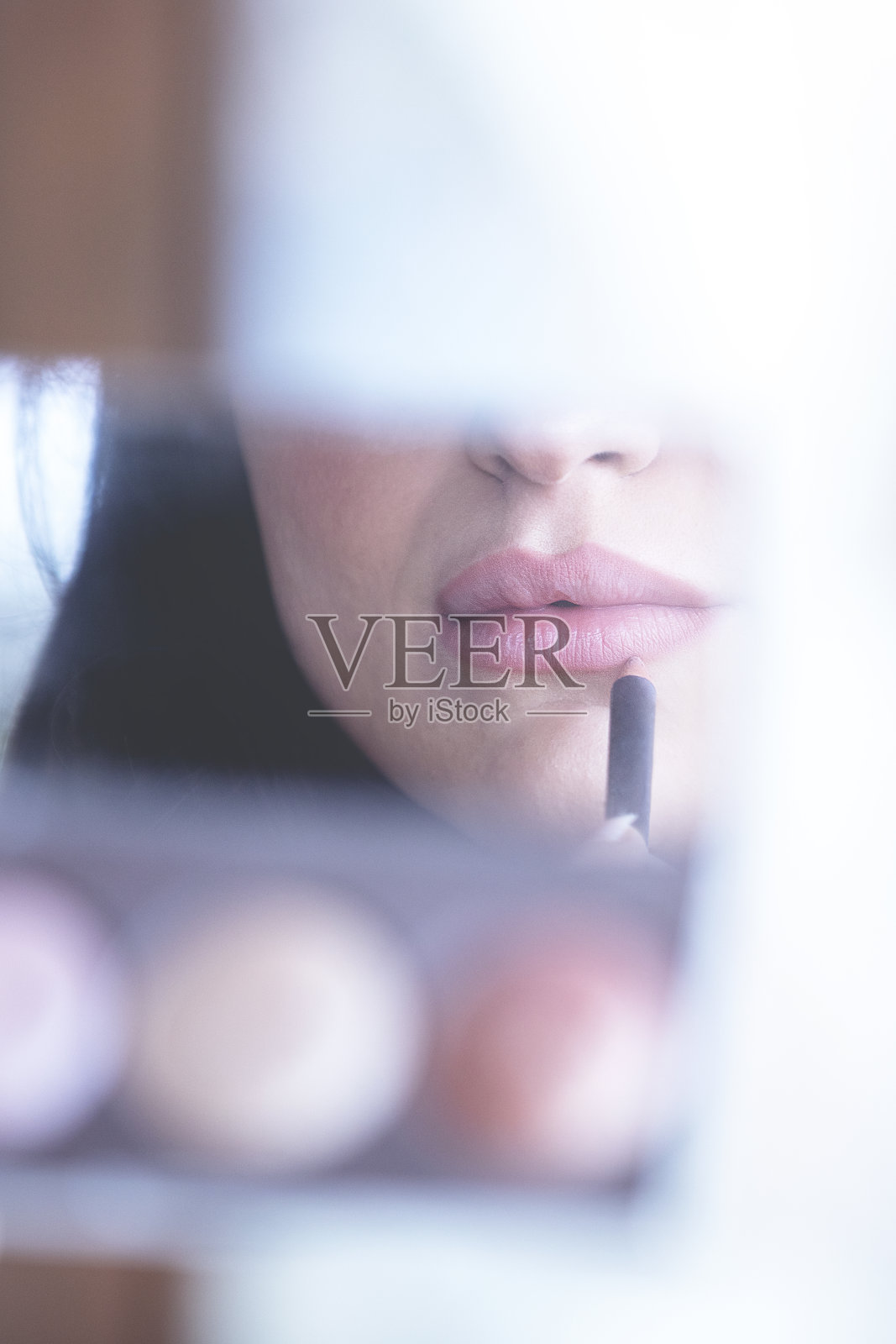 迷人的年轻女子化妆时看着镜子照片摄影图片