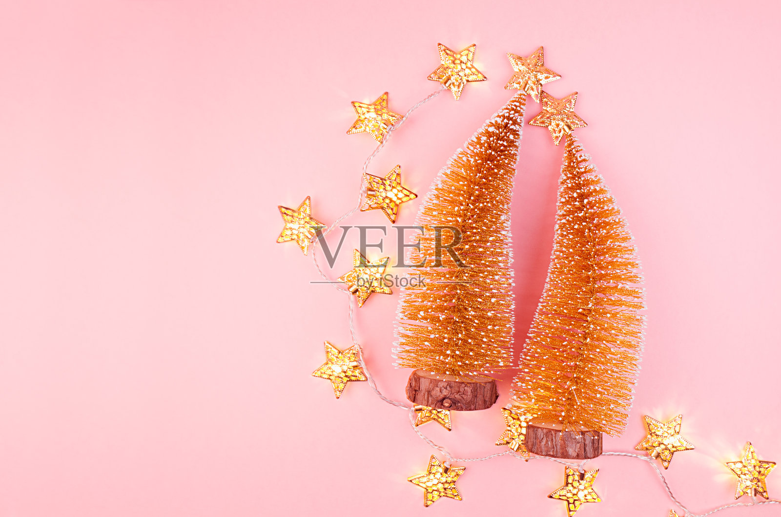 奢华的新年金色装饰与圣诞树，星星，发光的灯在柔和的淡粉色背景，顶视图。照片摄影图片