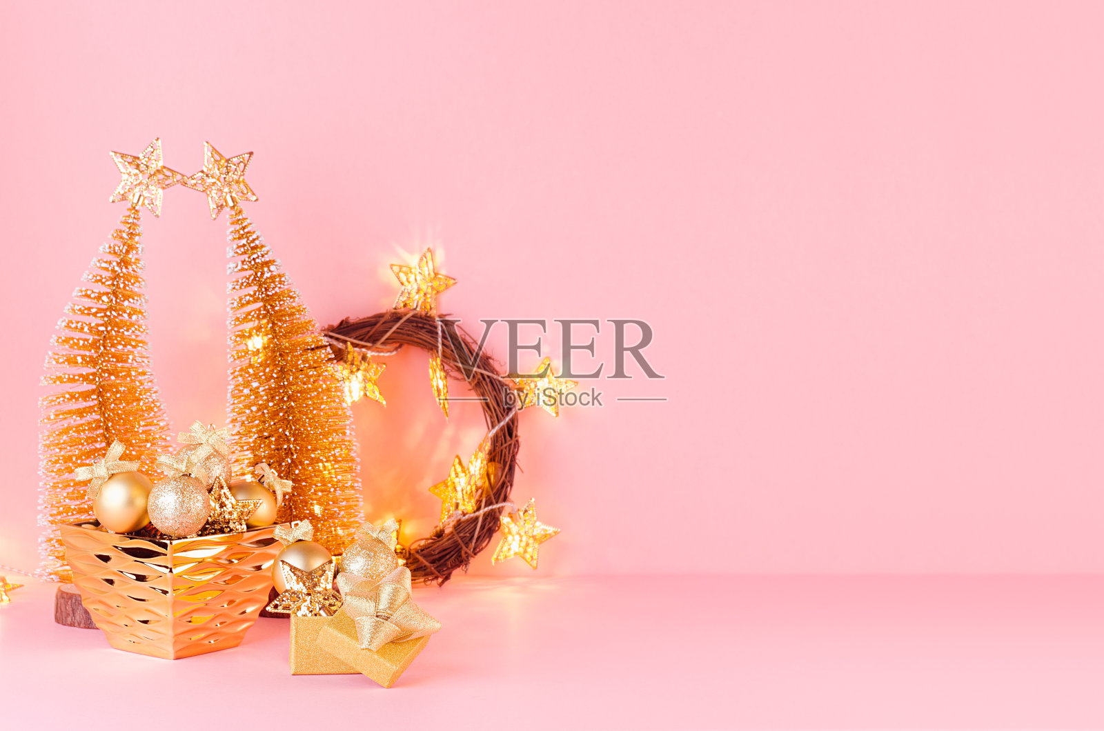 圣诞节明亮而温柔的背景用闪闪发光的金色装饰，圣诞树、花环、彩灯以淡雅的粉色为背景。照片摄影图片