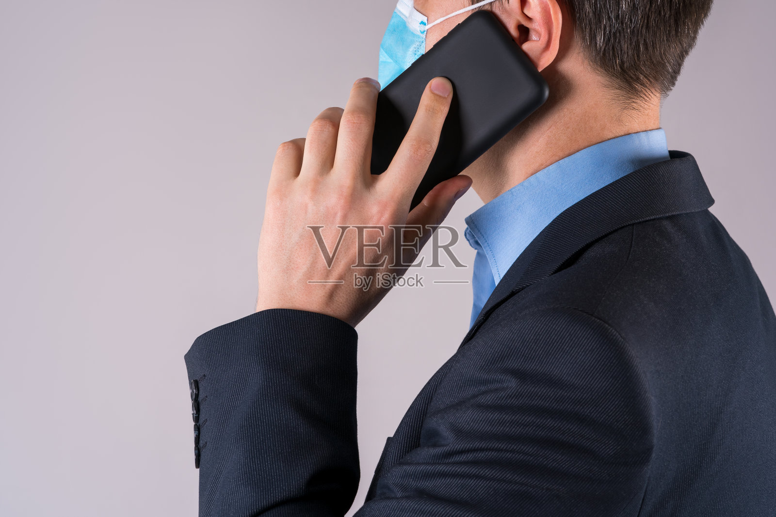 灰色背景下带着防护面罩的手机的办公室职员照片摄影图片