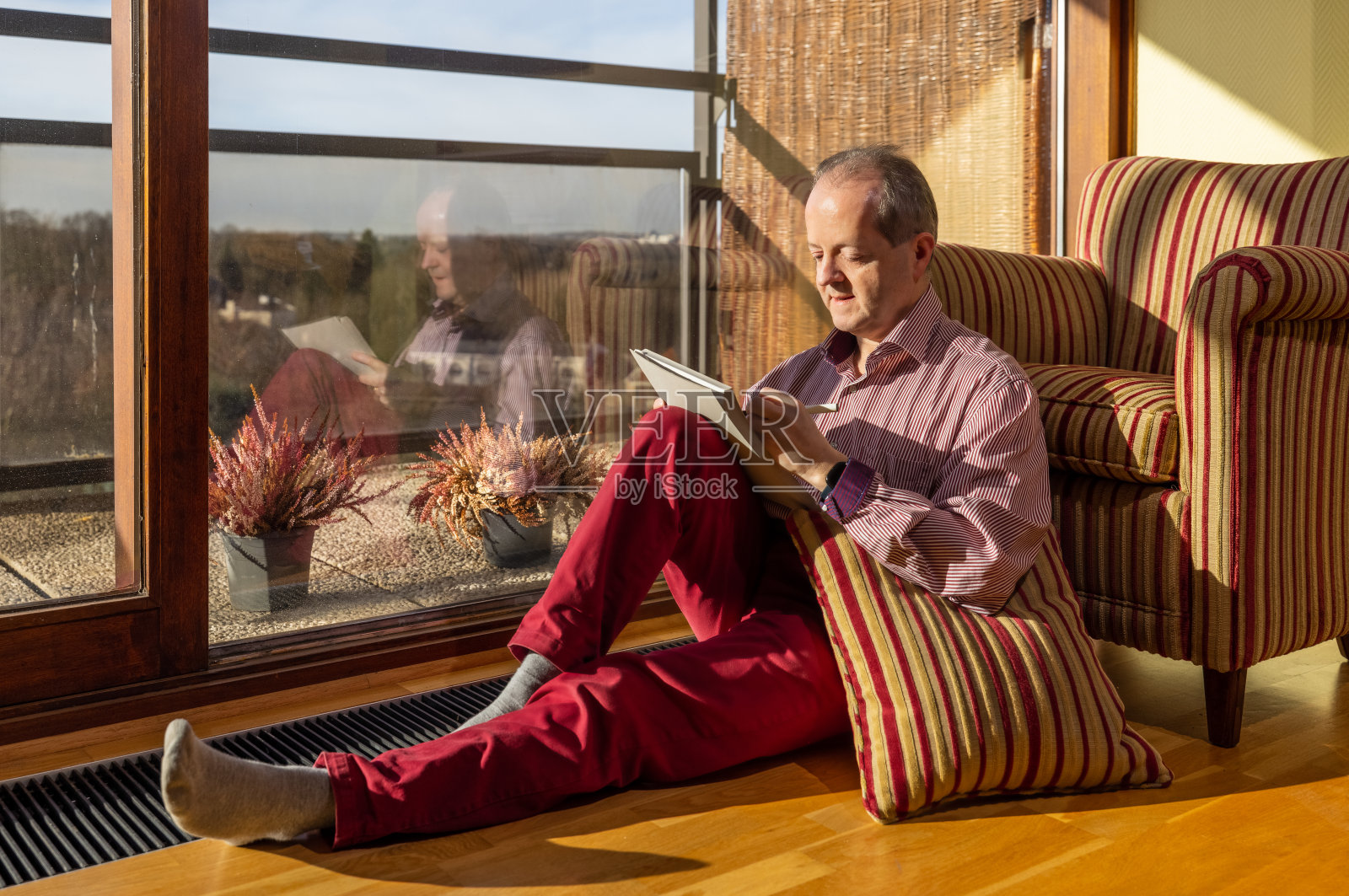 一位中年白人老人坐在客厅里，靠在扶手椅上，在他的记事本上写着什么照片摄影图片