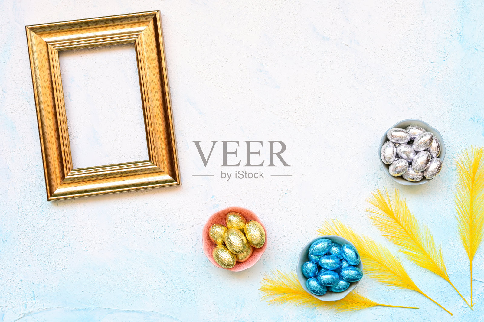 贺卡巧克力复活节蛋在一个碗与金色复古角落彩色羽毛在浅蓝色背景与复制空间照片摄影图片