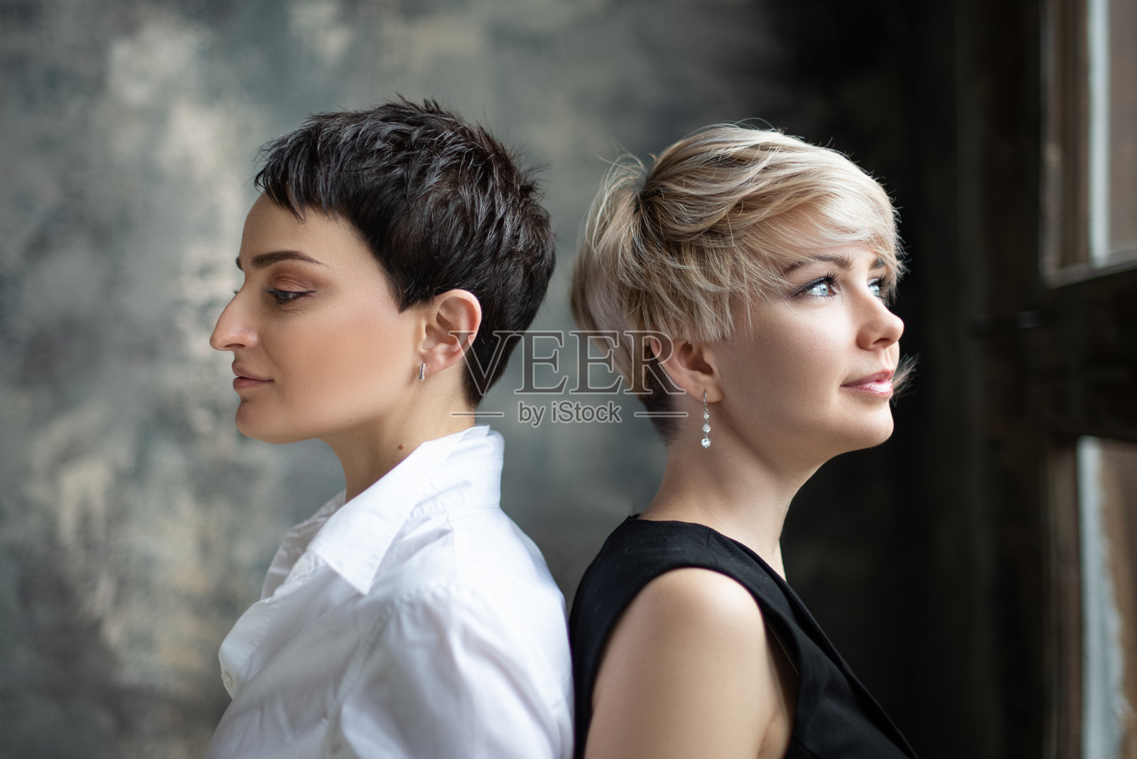 两个金发和黑发的年轻女孩背对着站着照片摄影图片