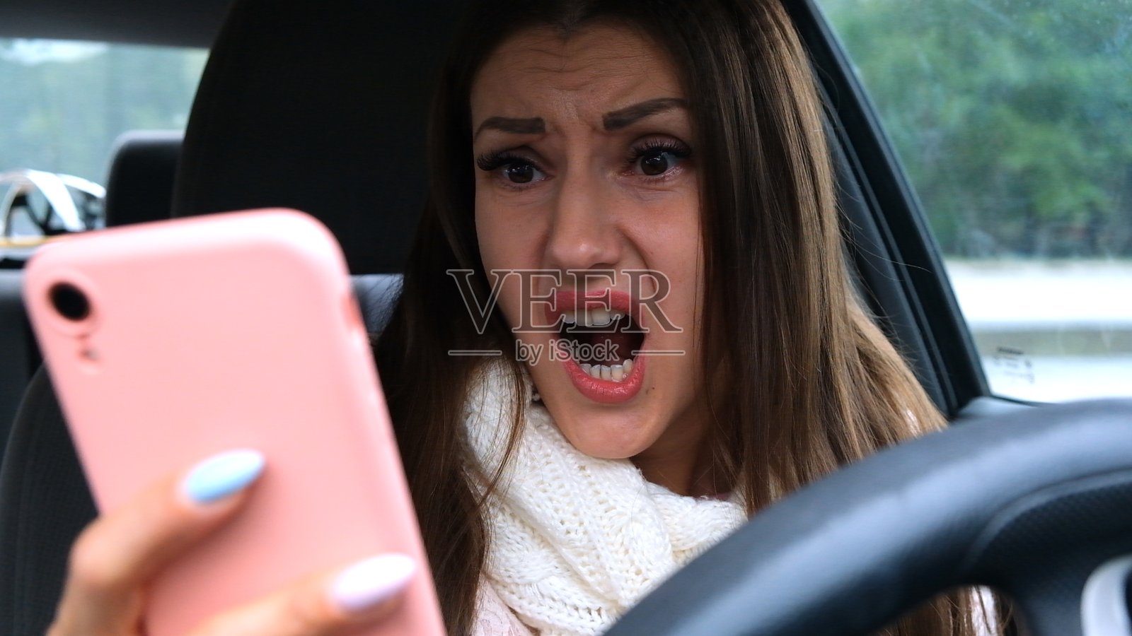 一位在开车时使用智能手机的女性感到惊讶和不安。坏消息的概念照片摄影图片