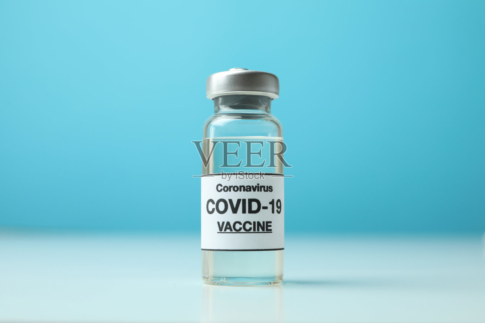 蓝色背景下的小瓶Covid - 19疫苗照片摄影图片