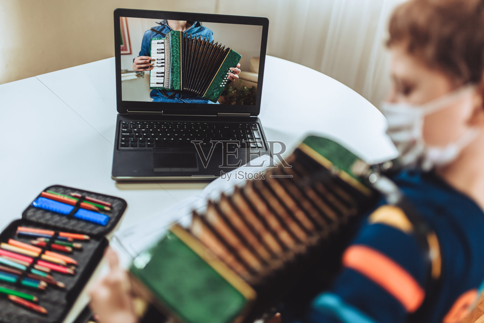 专注的男孩一边在家练习，一边在笔记本电脑上玩手风琴吉他和看在线课程。在线培训，在线课程。照片摄影图片
