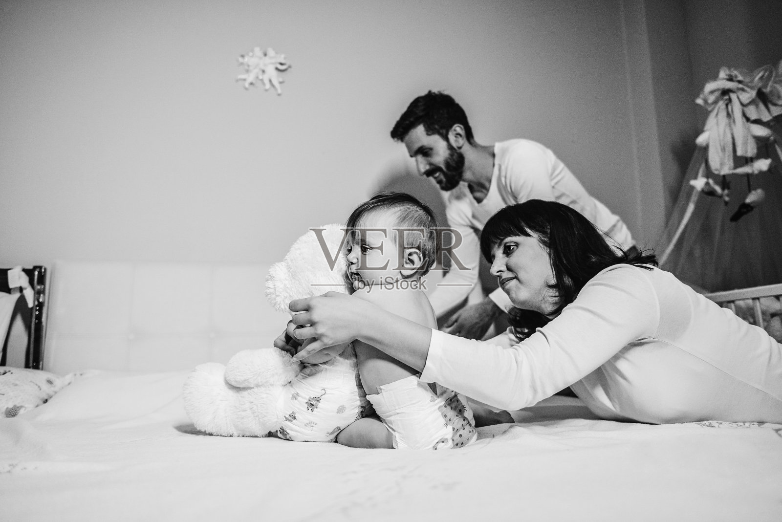 小女孩坐在床上玩泰迪熊照片摄影图片