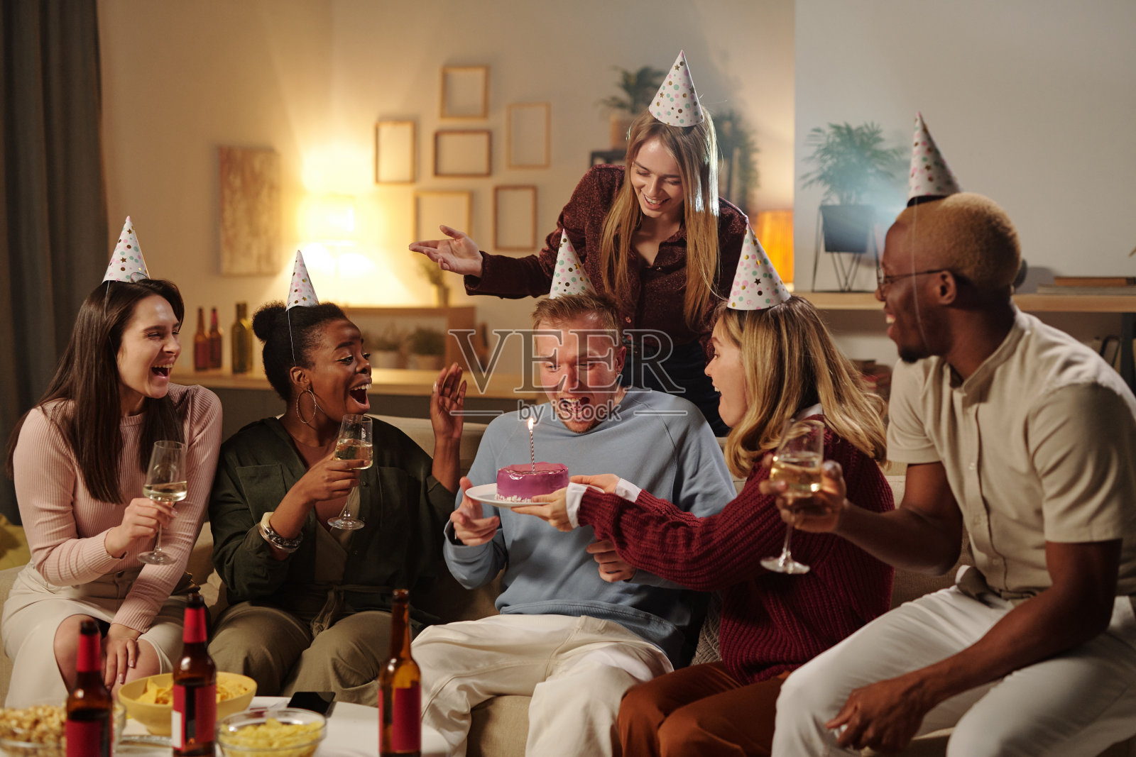 快乐的年轻的跨文化朋友祝贺兴奋的男孩的生日照片摄影图片