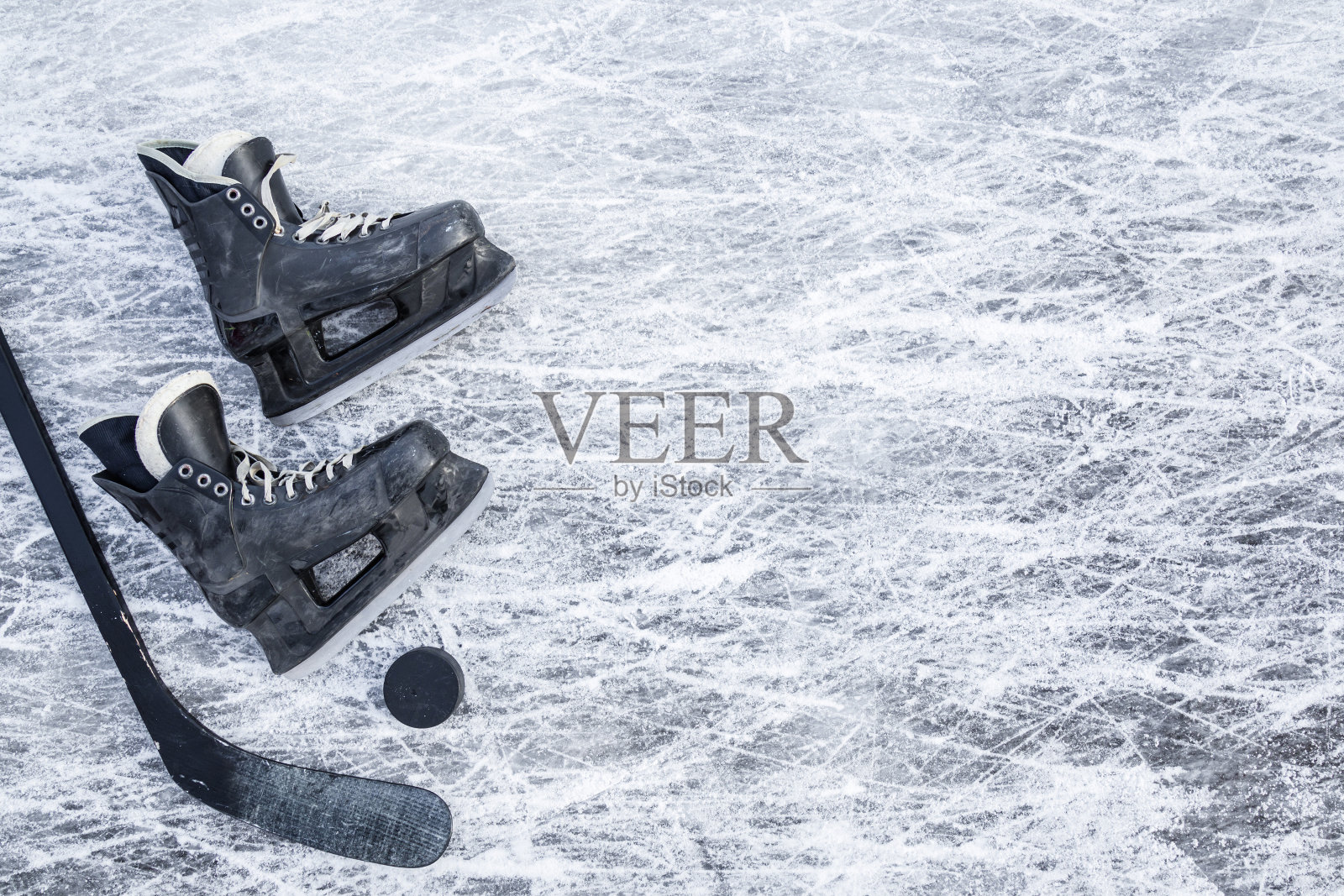 老划痕的黑人曲棍球男性溜冰鞋，棍和橡胶冰球在冰上的背景。特写镜头。文本的空位置。自顶向下的观点。照片摄影图片