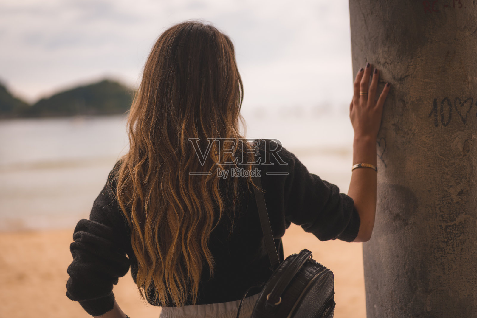 在城市的生活方式和一个金发女孩白色裤子和皮夹克附近的海滩。阿波拉达排成纵队望着大海照片摄影图片