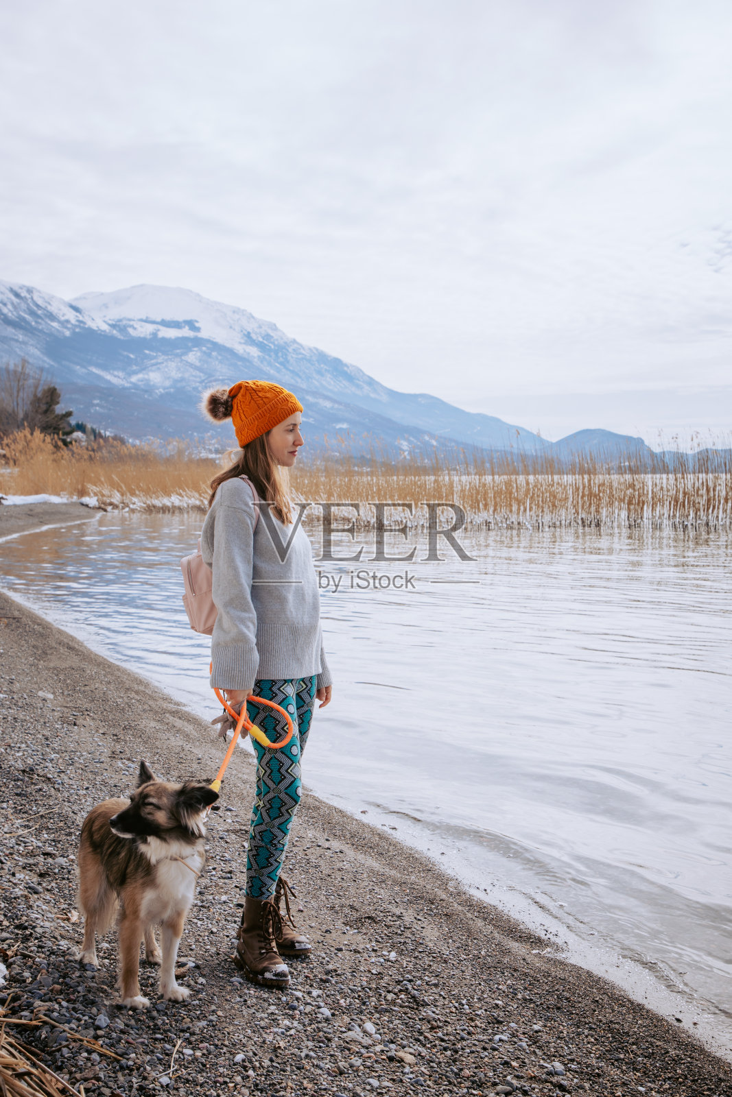 冬天，一个女人在湖边遛狗照片摄影图片