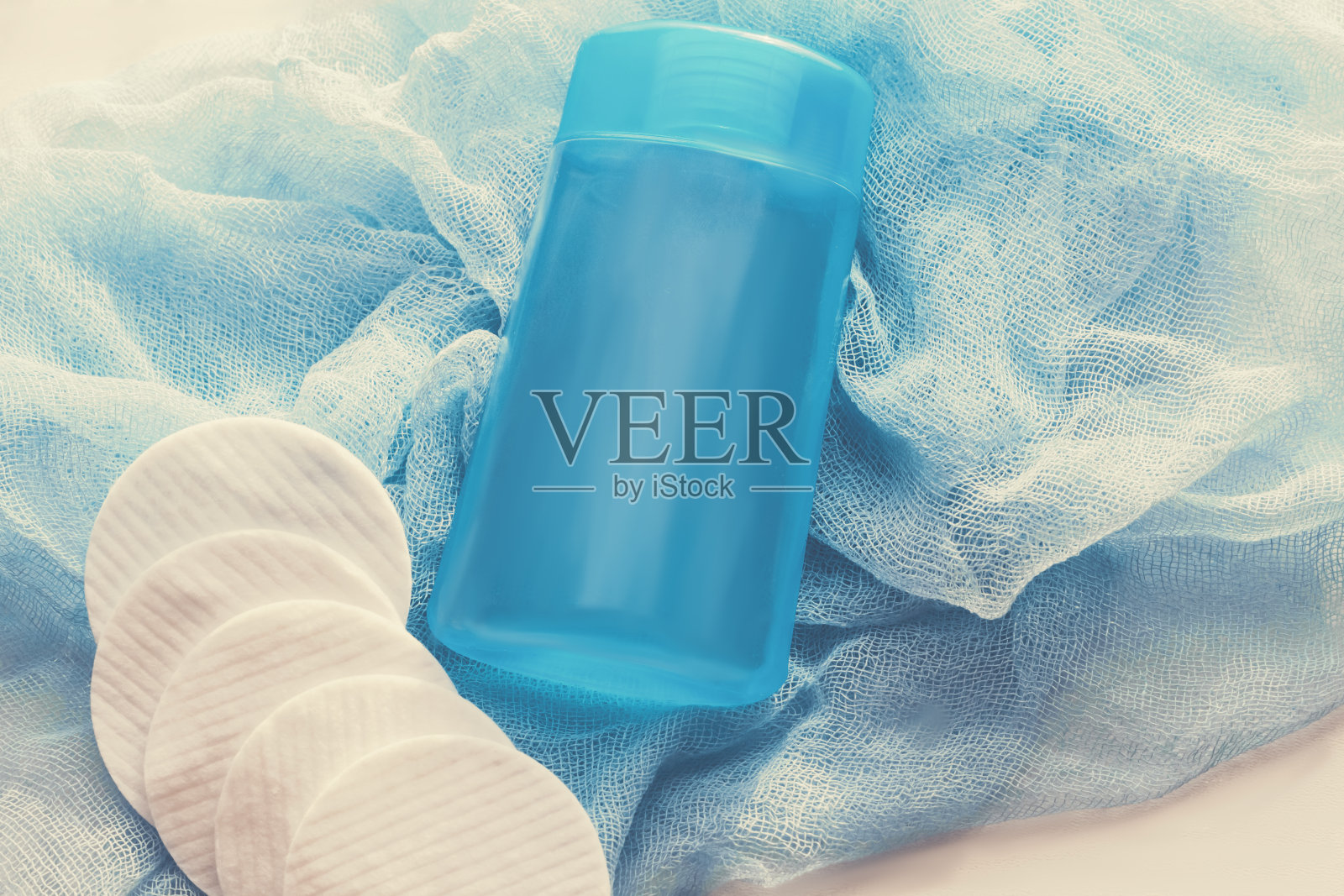 胶束水在蓝色瓶子与棉花圆盘，以消除化妆在蓝色背景。美丽的概念照片摄影图片