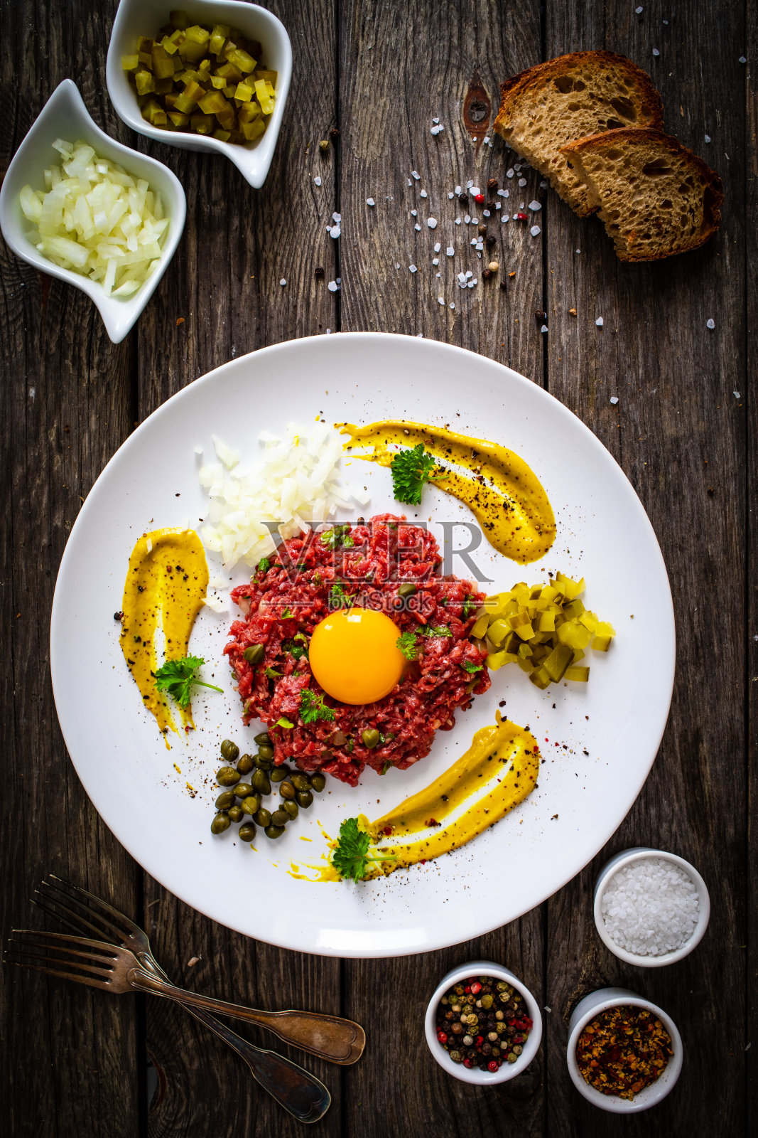 鞑靼牛肉配洋葱、酸豆和腌黄瓜放在木桌上照片摄影图片