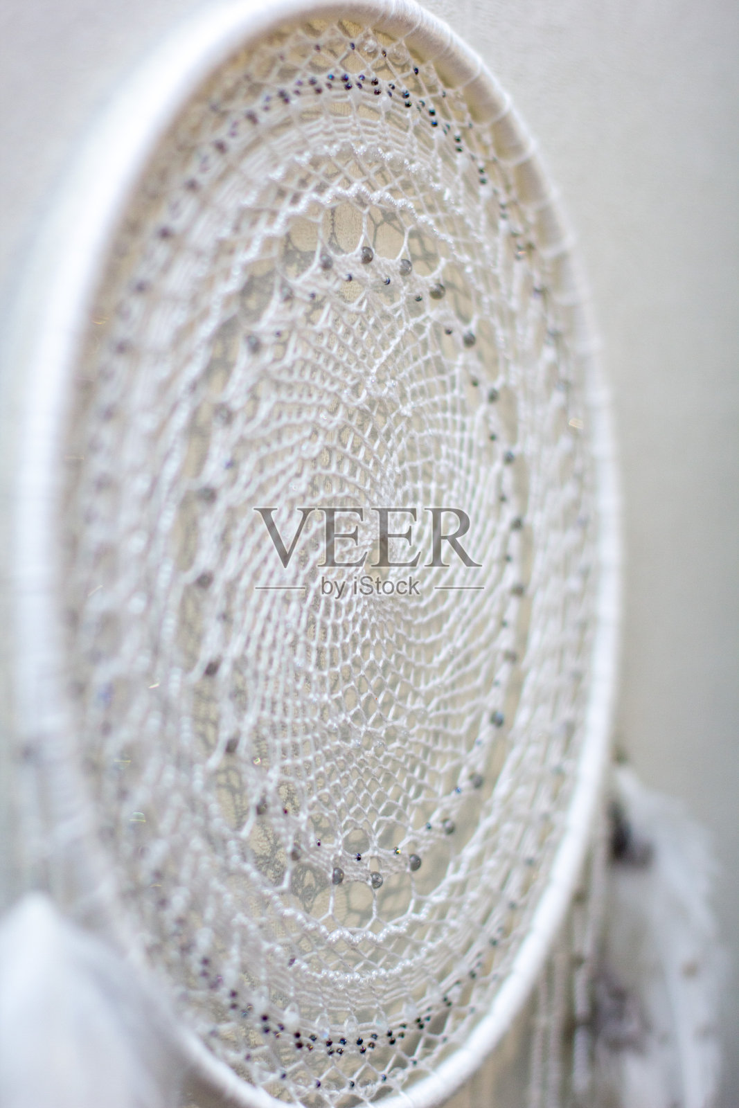 手工捕梦网，羽毛线和珠子绳挂在白色的背景上照片摄影图片