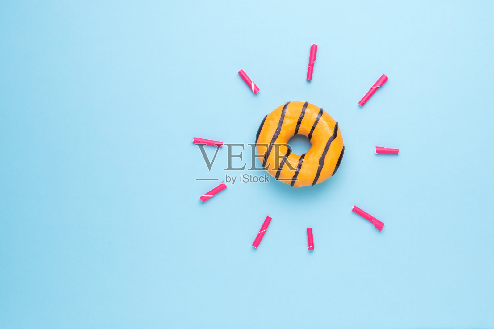 橙色的甜甜圈和光线从管子在蓝色的背景。照片摄影图片