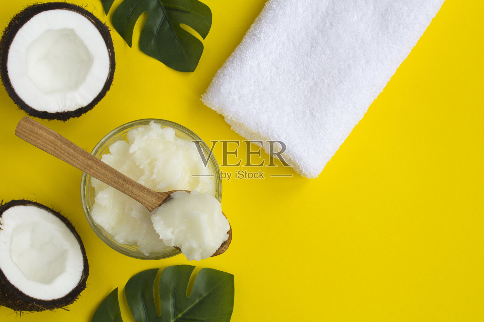 水疗中心组成。黄色背景上有椰子油，白色毛巾和椰子的一半照片摄影图片