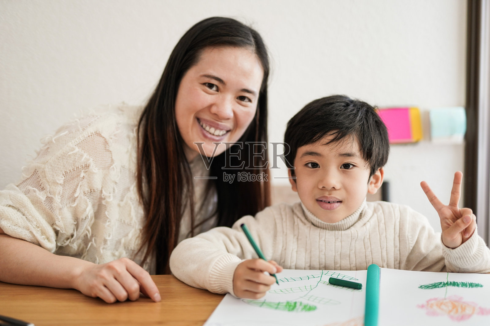 亚洲小男孩用手做和平手势-母子在室内一起画画照片摄影图片