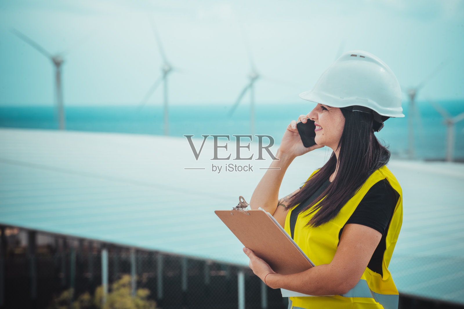 成年女性工程师在一个可再生能源综合设施中管理太阳能电池板和风车照片摄影图片