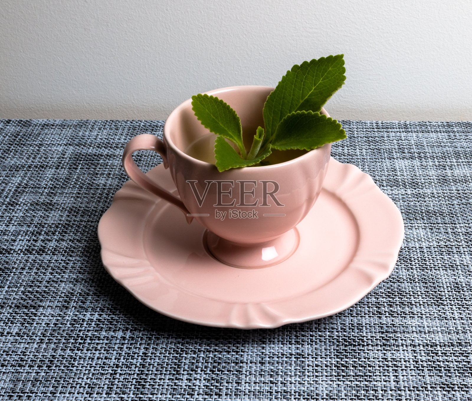越桔茶，在浅的背景和绿色的叶子上，在一个灰色的垫子上，粉红色的瓷杯，珀乌斯boldus。用于医疗目的和消化支持。照片摄影图片