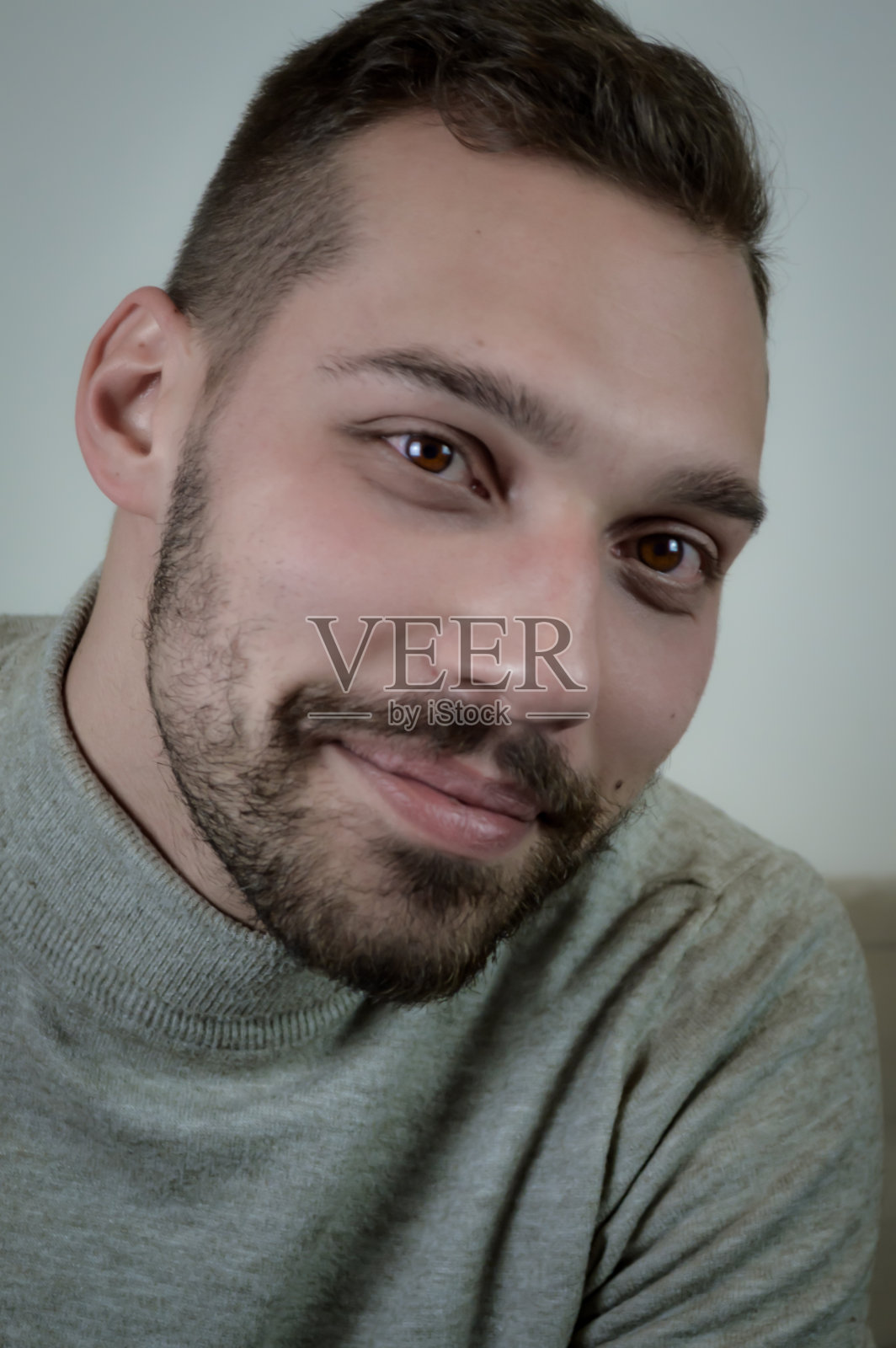 一个微笑的年轻男子的肖像棕色头发短胡子和灰色高领毛衣照片摄影图片