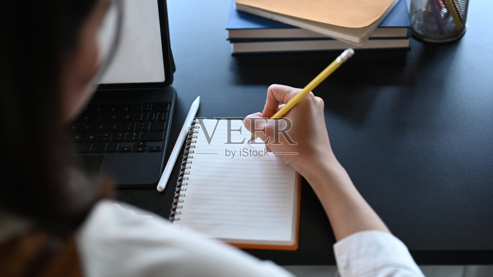 近距离观看年轻的女商人使用电脑平板电脑和写在空笔记本上。照片摄影图片